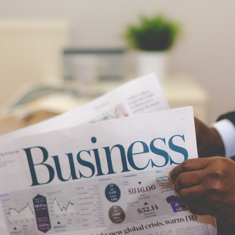 A person is holding a newspaper that says business