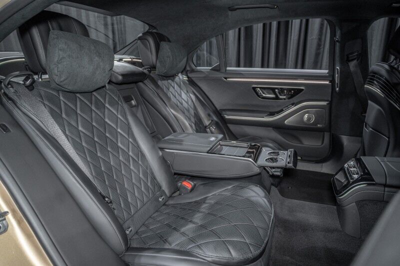 The back seats of a mercedes benz s class are black leather and have seat belts.