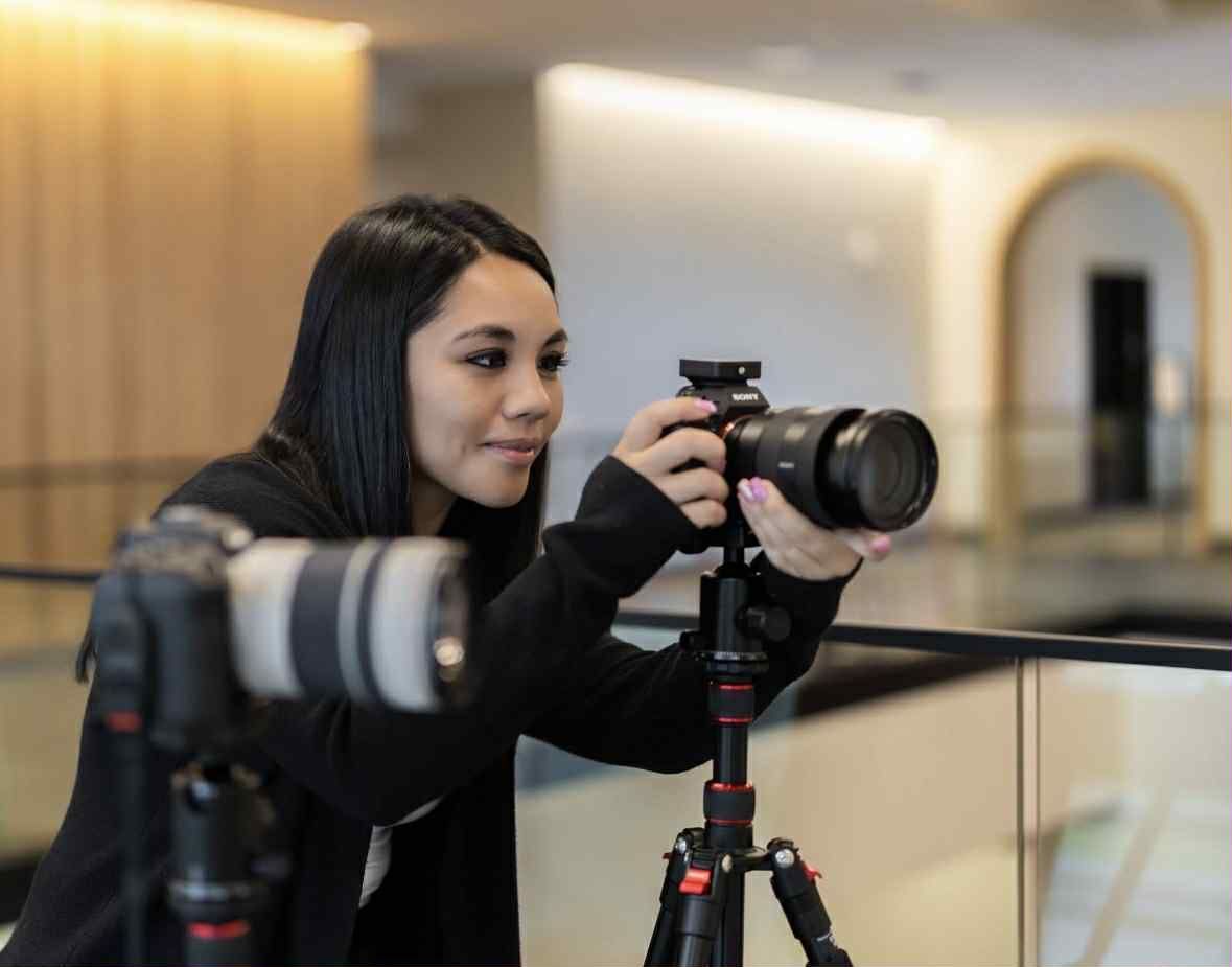 Woman with camera on tripod taking a photo inside building with another camera on tripod in front. Woman with camera on tripod taking a photo inside building with another camera on tripod in front.