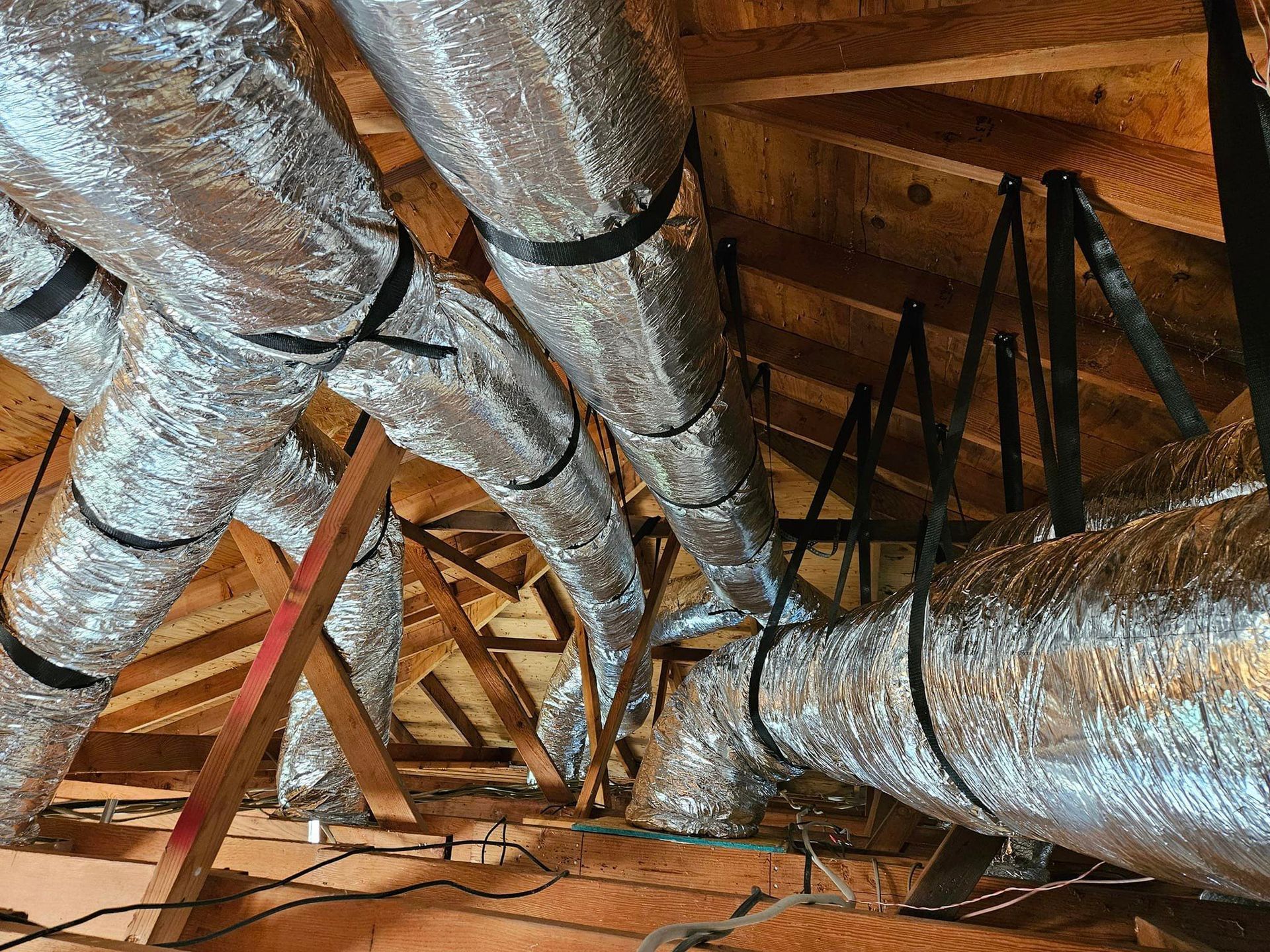 A bunch of ducts are hanging from the ceiling of a building.
