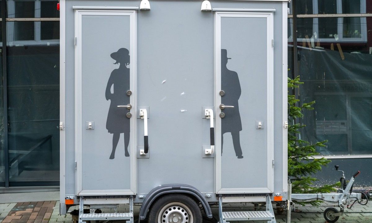 An outdoor restroom trailer with a figure of a man and woman on the respective doors.