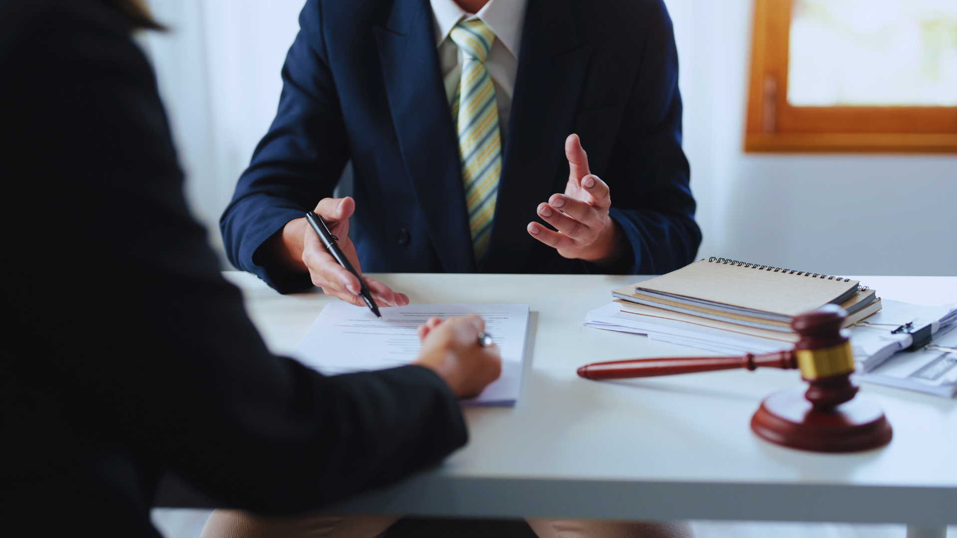 Business meeting at a desk with two people discussing documents and a gavel in the foreground