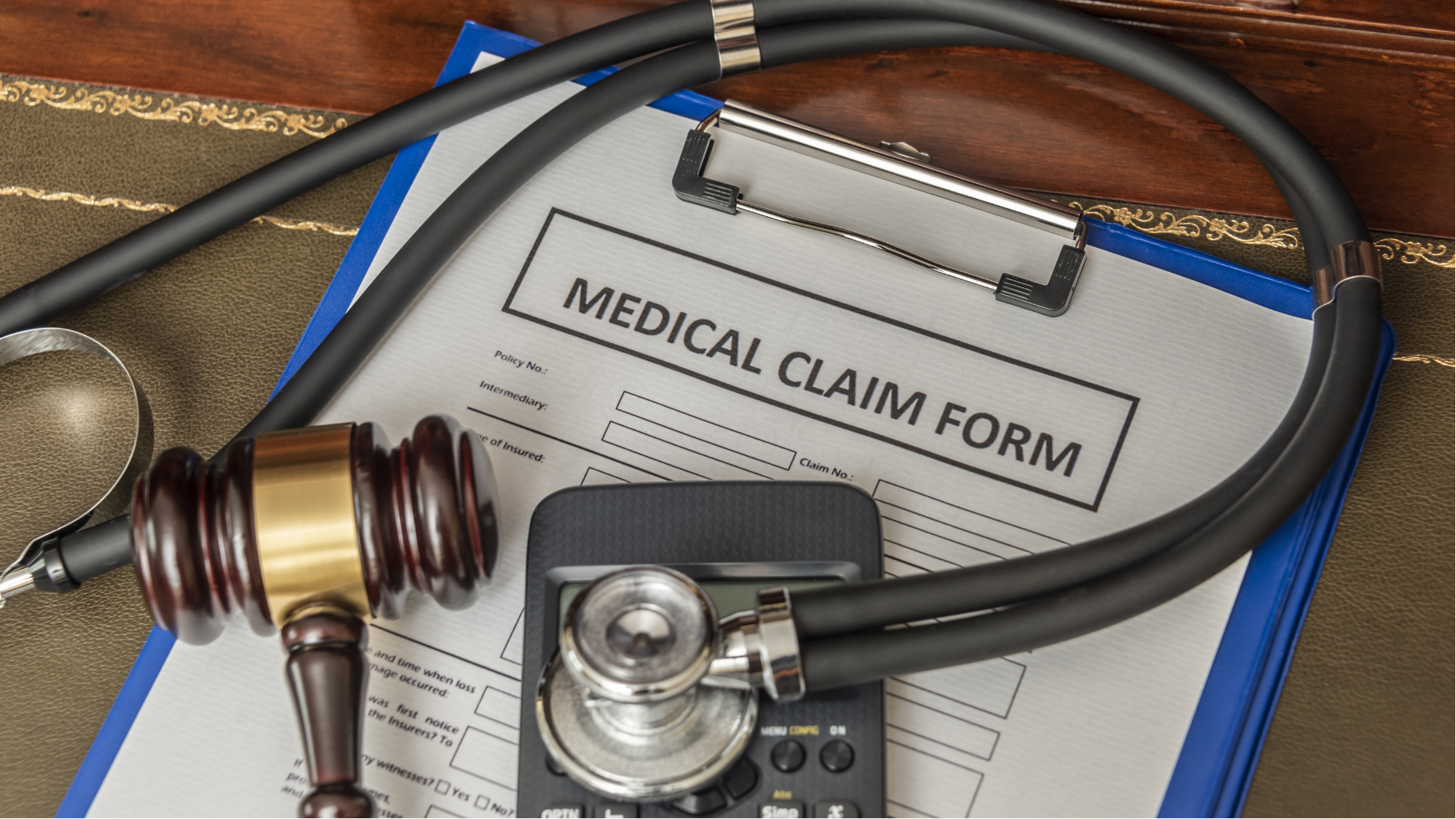 Medical claim form with stethoscope and gavel on a blue clipboard