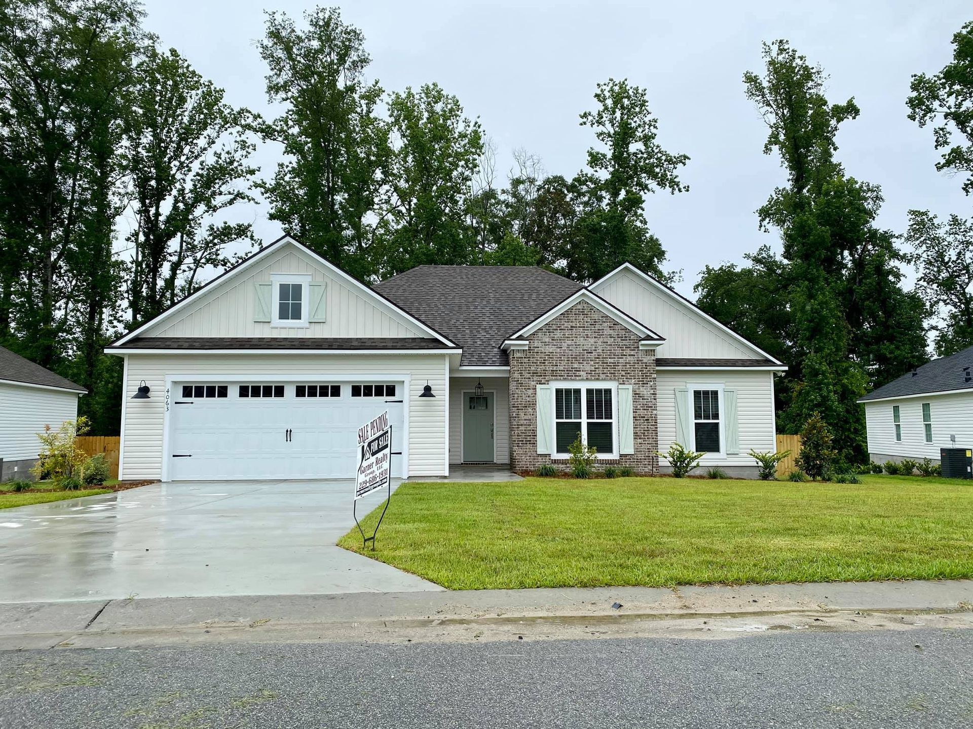 White suburban house with gray roof, green lawn, and overcast sky.
