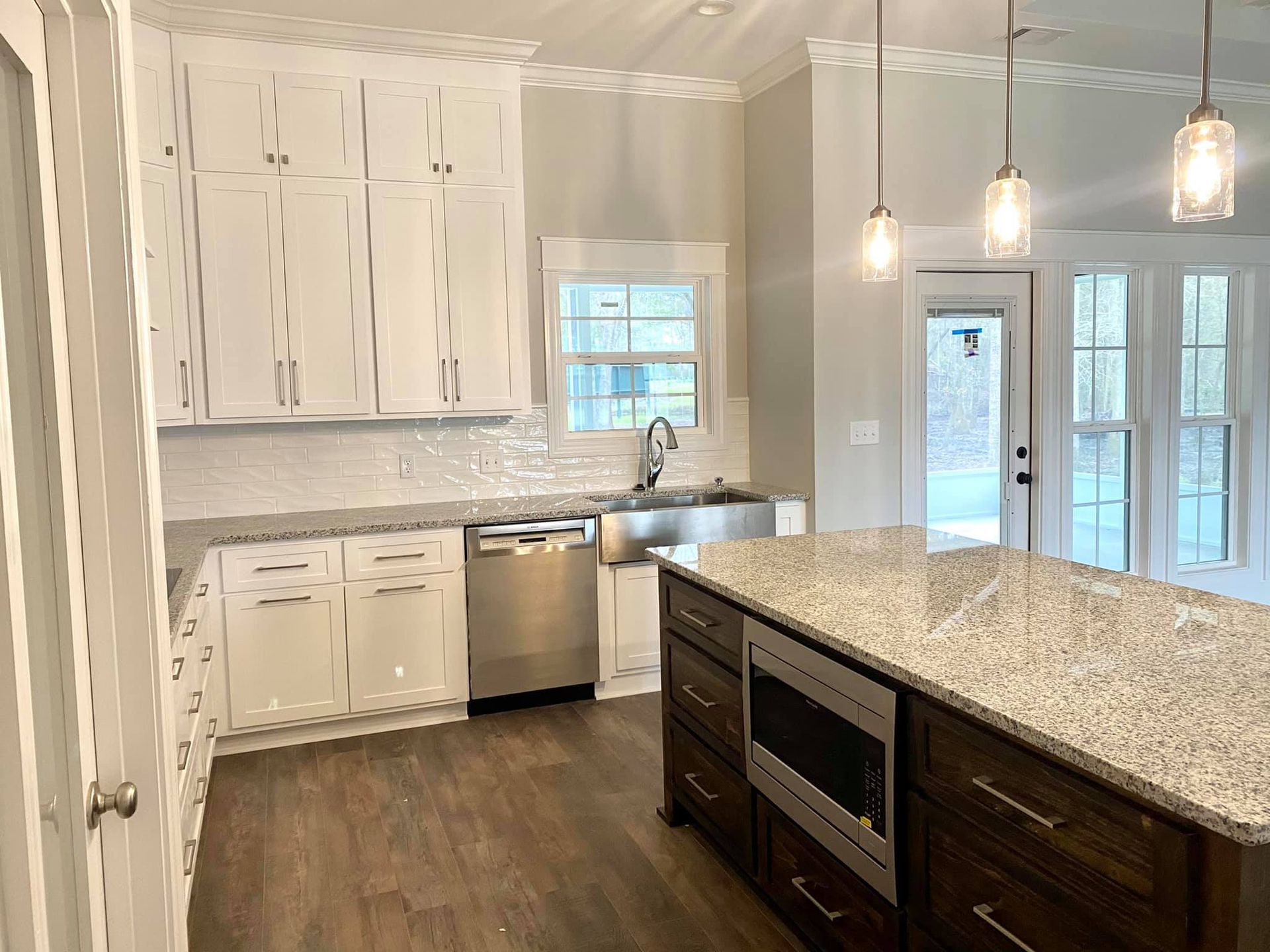 Kitchen with white cabinets, stainless steel appliances, granite countertops, and dark wood island.