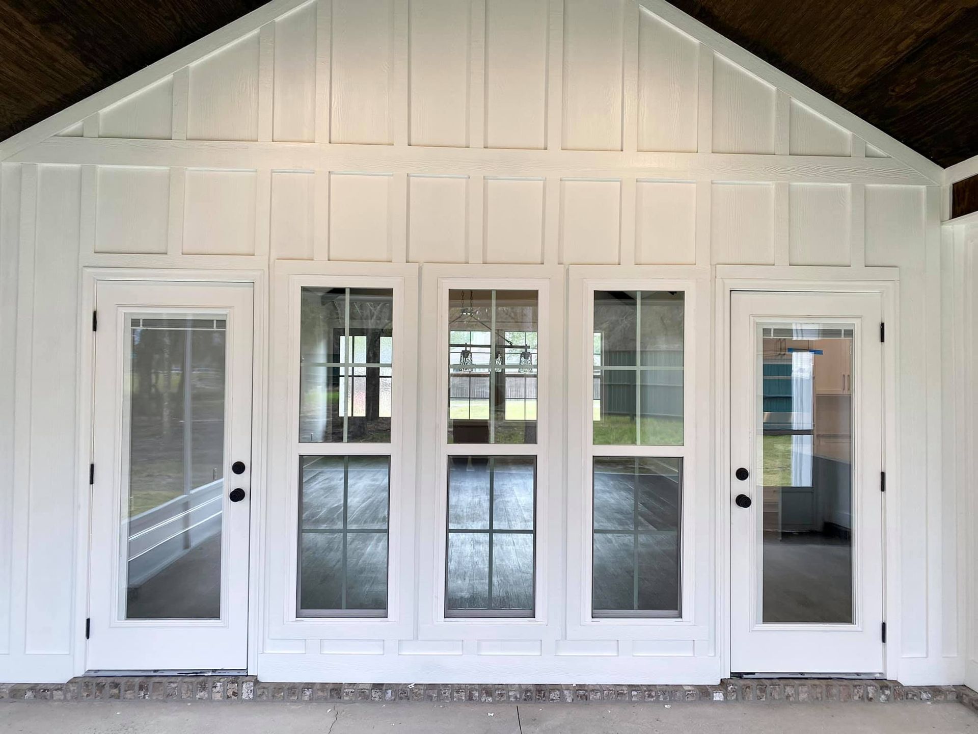 White French doors with clear glass panels, surrounded by white paneling, and a concrete patio.