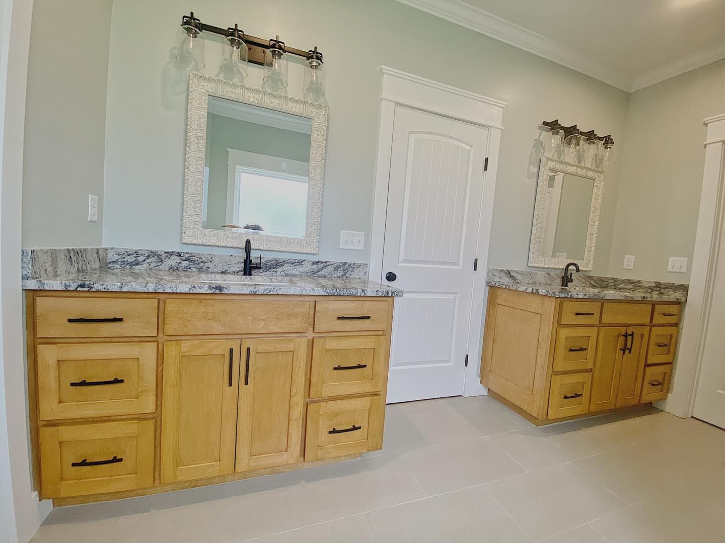 Two wood vanities with granite countertops in a light green bathroom.