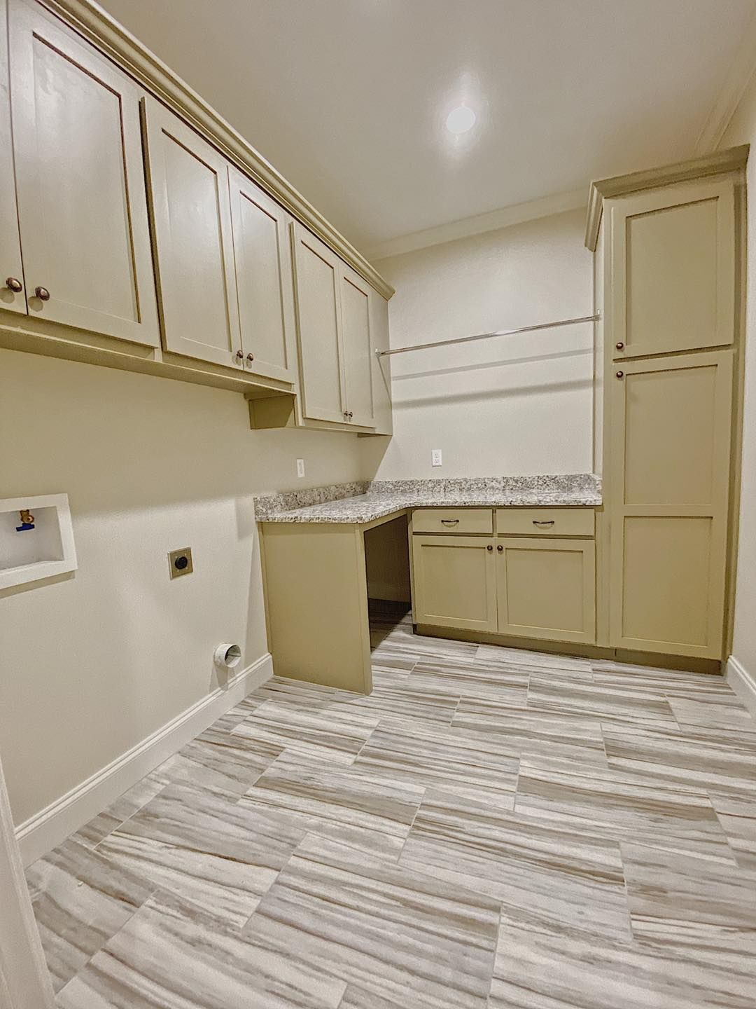 Laundry room with light-colored cabinets, countertops, and tile floor. Includes built-in desk and tall storage.
