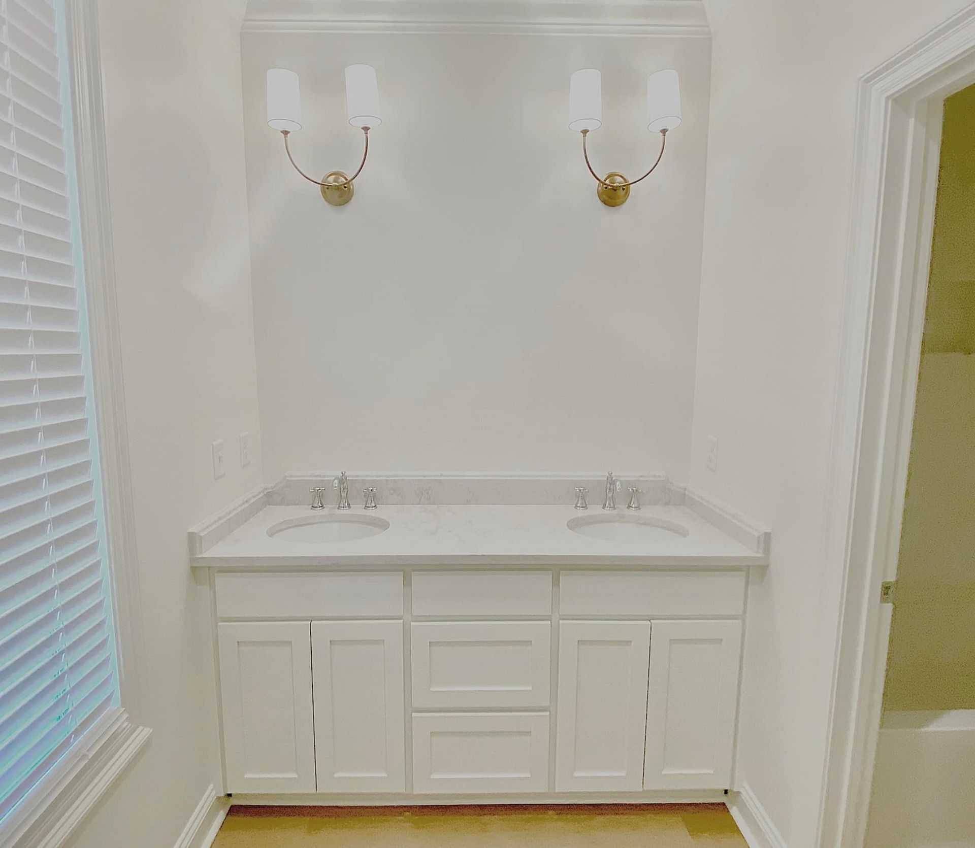 White double sink vanity with two sconces above, set in a bright bathroom.