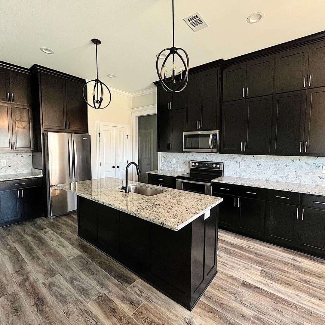 Kitchen with dark cabinets, island, stainless steel appliances, and patterned backsplash.