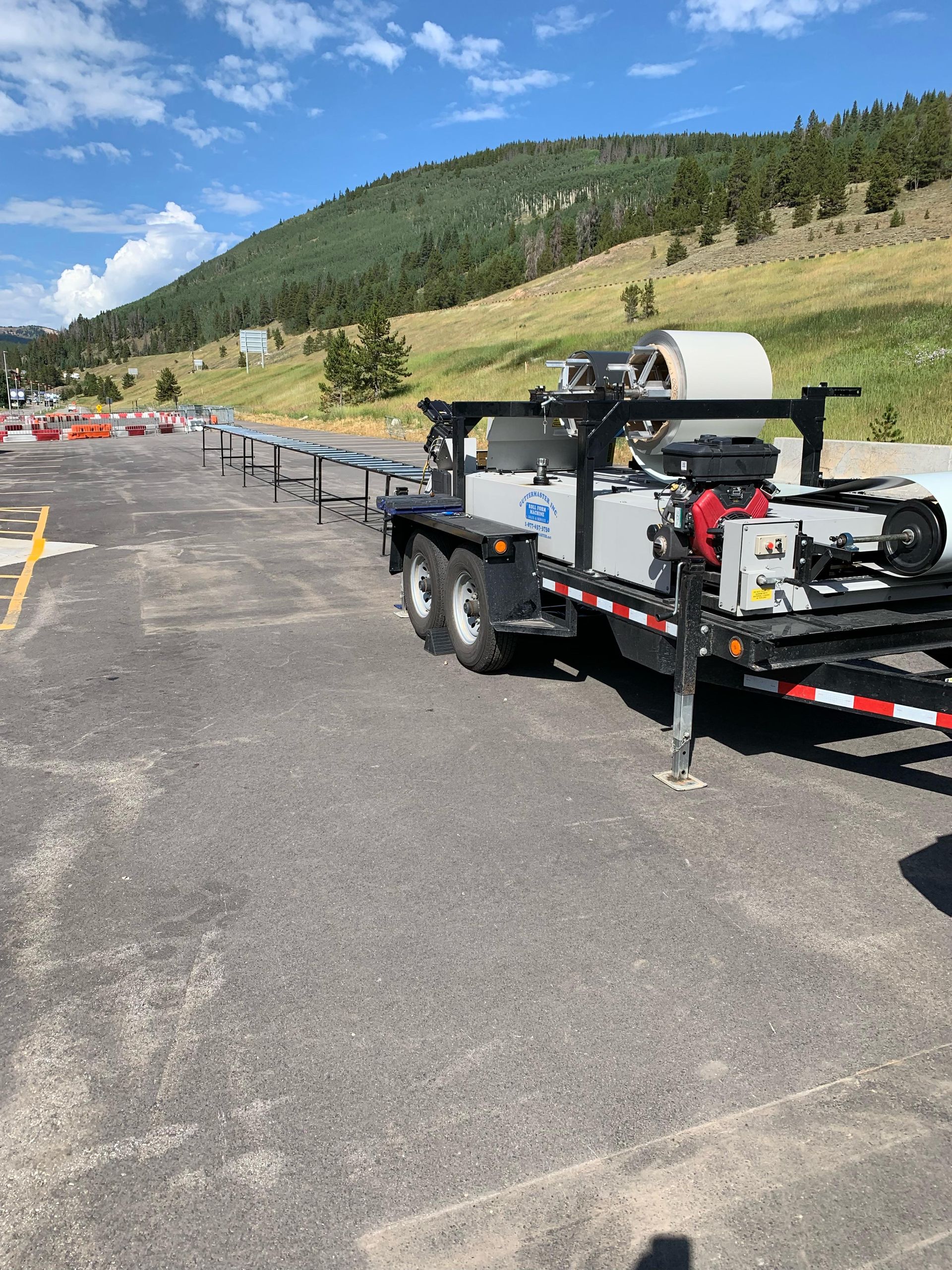 A trailer is parked in a parking lot with mountains in the background