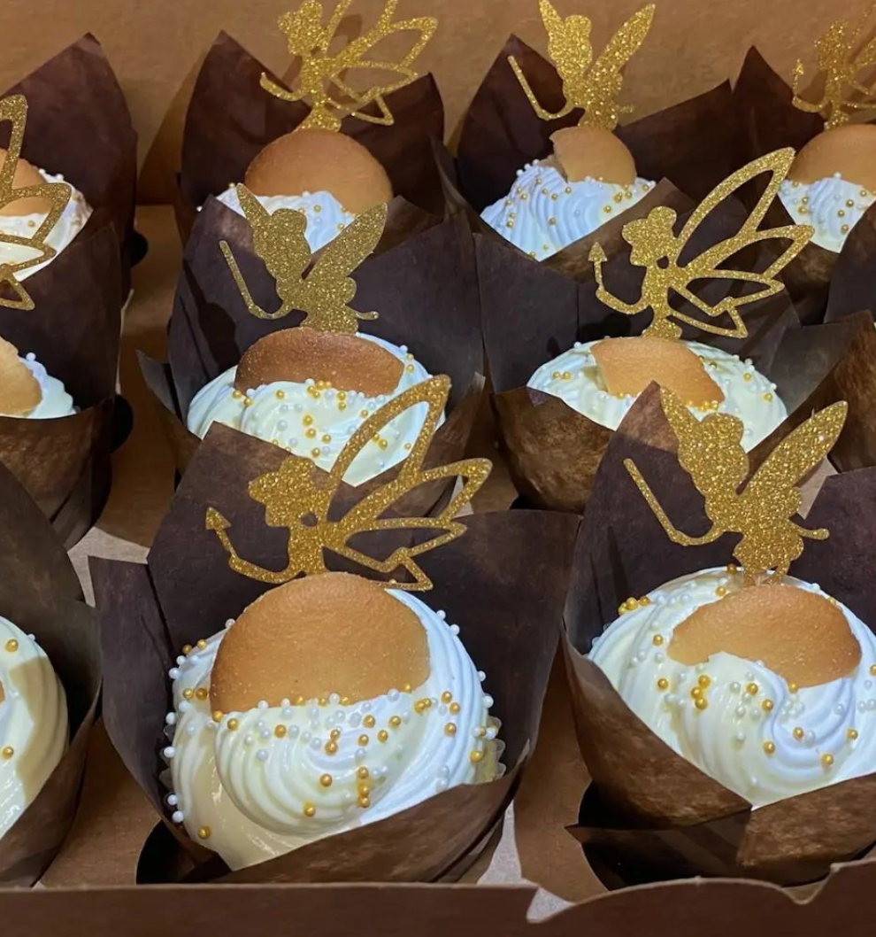 A box of cupcakes with fairy decorations on them
