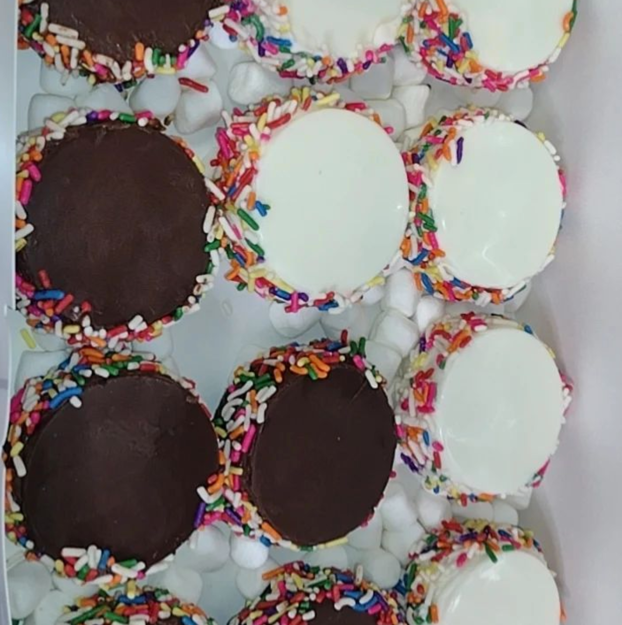 A box of cupcakes with chocolate frosting and sprinkles