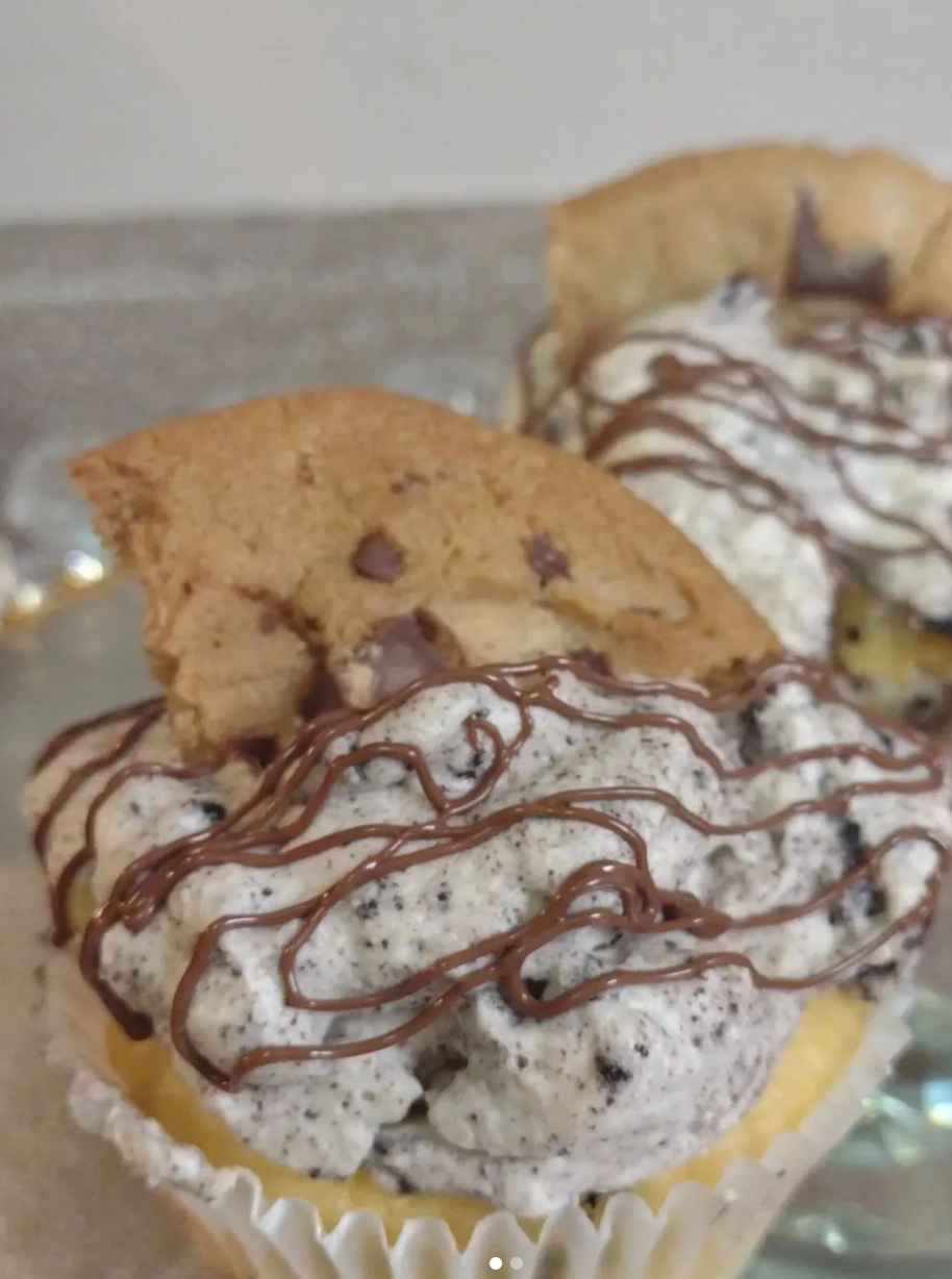 A close up of a cookie dough cupcake with chocolate drizzle