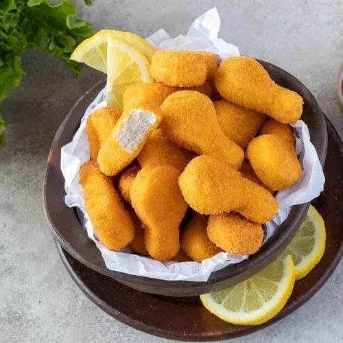 Un tazón de nuggets de pollo con rodajas de limón en un plato.