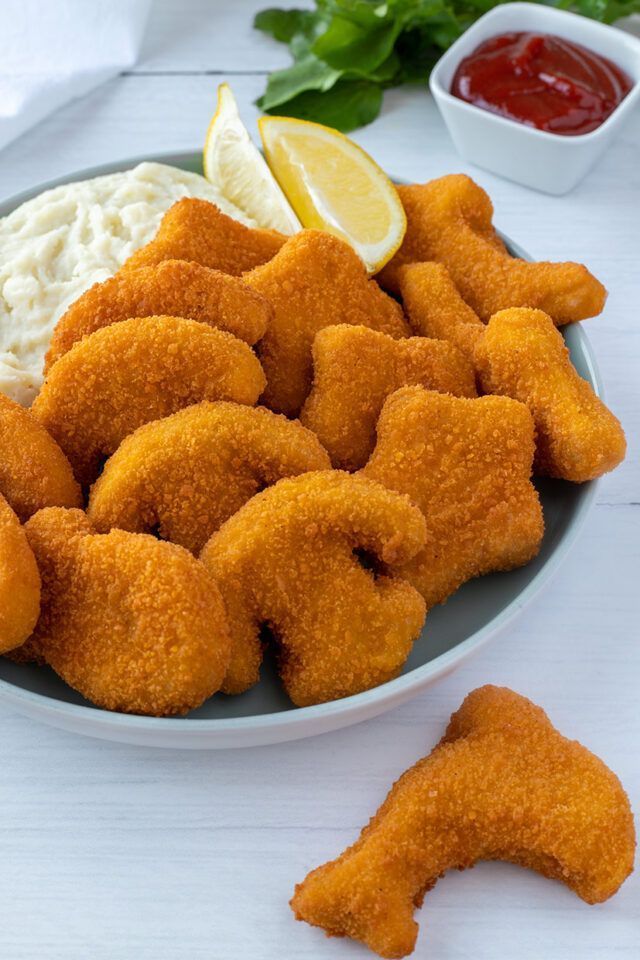 Un plato de camarones fritos con mayonesa y salsa de tomate sobre una mesa.