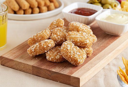 Los nuggets de pollo están sobre una tabla de cortar de madera.