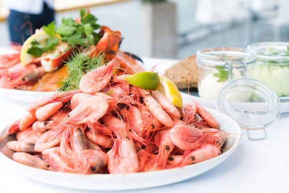 Un plato de camarones con una rodaja de limón sobre una mesa.