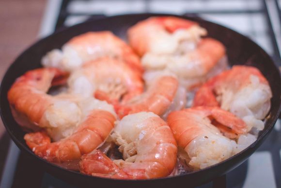 Los camarones se cocinan en una sartén sobre una estufa.