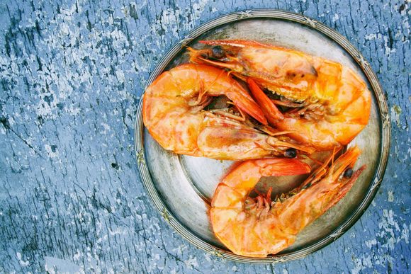Un plato de camarones cocidos sobre una mesa azul.
