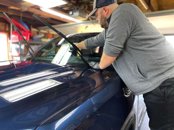 a man is cleaning the windshield of a blue truck in a garage .