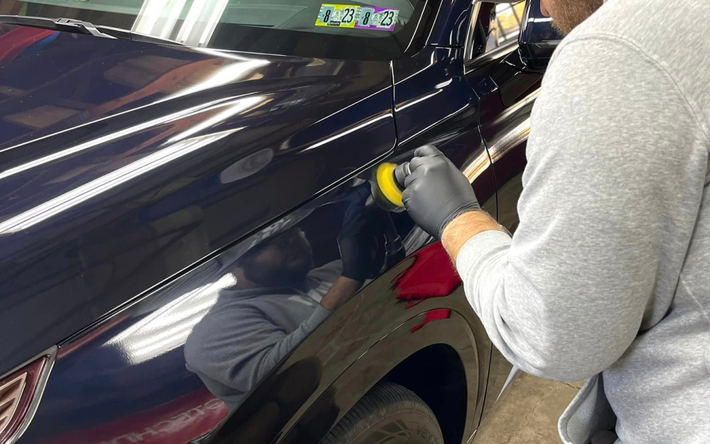 a man is polishing a black truck in a garage .