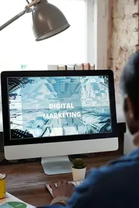 Person at desk viewing “Digital Marketing” on desktop computer in a modern office