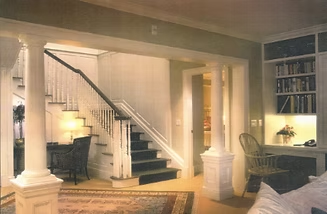 Interior with staircase, columns, built-in shelves, and desk. Beige walls and white trim.