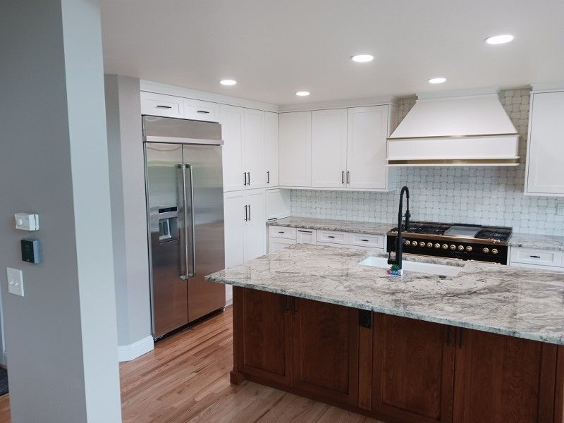 Modern white kitchen with stainless steel appliances, granite countertops, and wooden island.