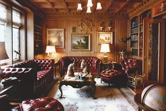 Luxurious wood-paneled study with red leather furniture, paintings, lamps, a rug, and a globe.