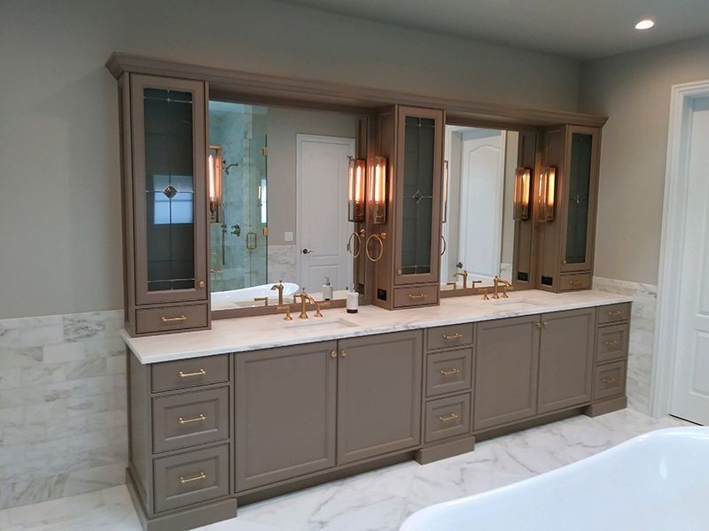 Custom gray bathroom vanity with mirrors, cabinets, and sconces.