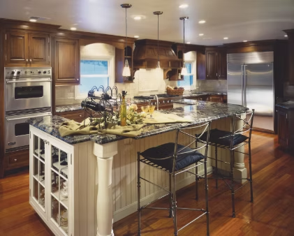 Kitchen with dark wood cabinets, granite island, stainless steel appliances, and wood flooring.