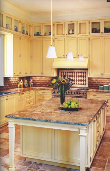 Yellow kitchen with island, cabinets, brick backsplash, and granite countertop.