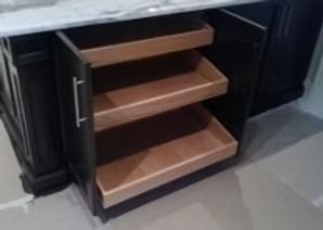 Dark cabinet with three pull-out shelves beneath a countertop.