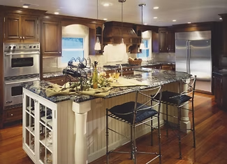 Kitchen with dark wood cabinets, granite countertops, island with seating, and stainless steel appliances.