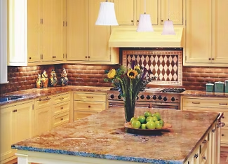 Yellow kitchen with brown countertops, island, and backsplash. Flower arrangement and fruit.