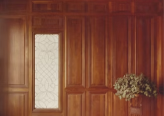 Wooden paneled wall with a decorative window and a plant in a pot.