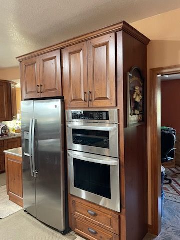 Modern kitchen with light wood cabinets, dark island, stainless steel appliances, and pendant lights.