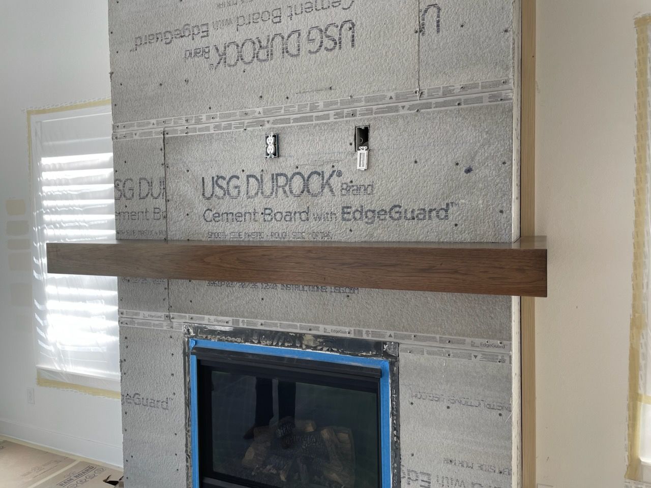 Living room with a fireplace, TV, floating shelves, and cabinets. Includes an armchair and rug.