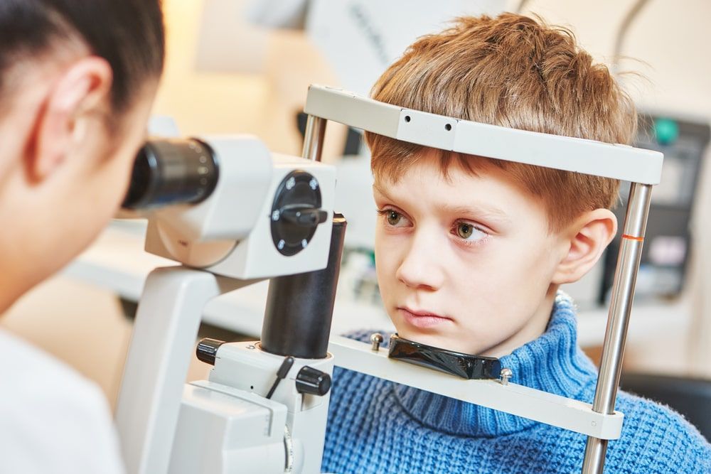 A Young Boy Is Getting His Eyes Examined By An Ophthalmologist — Mullumbimby Optometrist In Mullumbimby, NSW