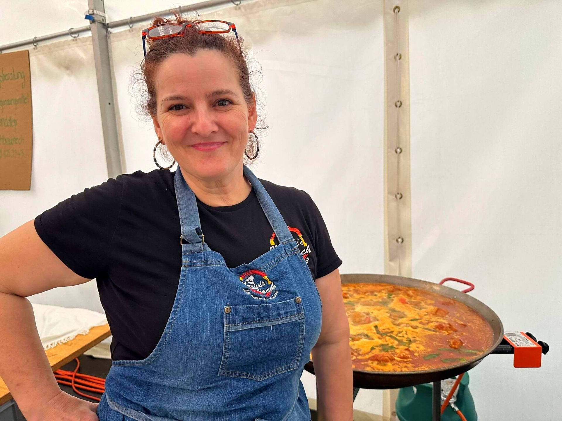 Mariví con delantal está parada frente a una sartén con comida en Suiza