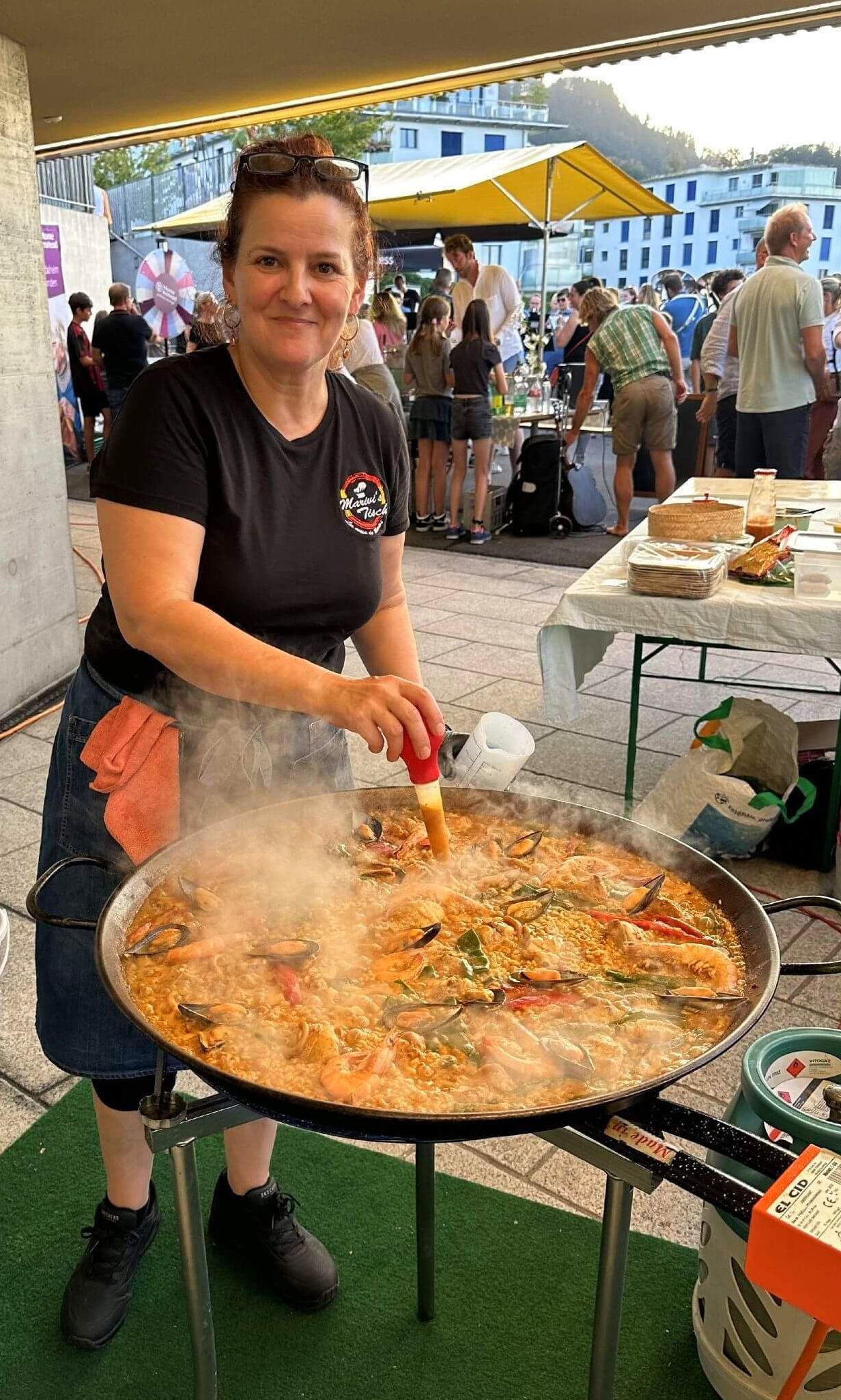 Mariví está cocinando comida en una sartén grande en un mercado en Suiza
