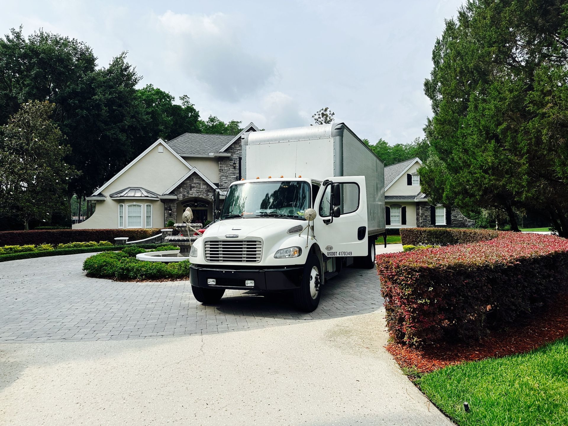 A white moving truck is parked in front of a house