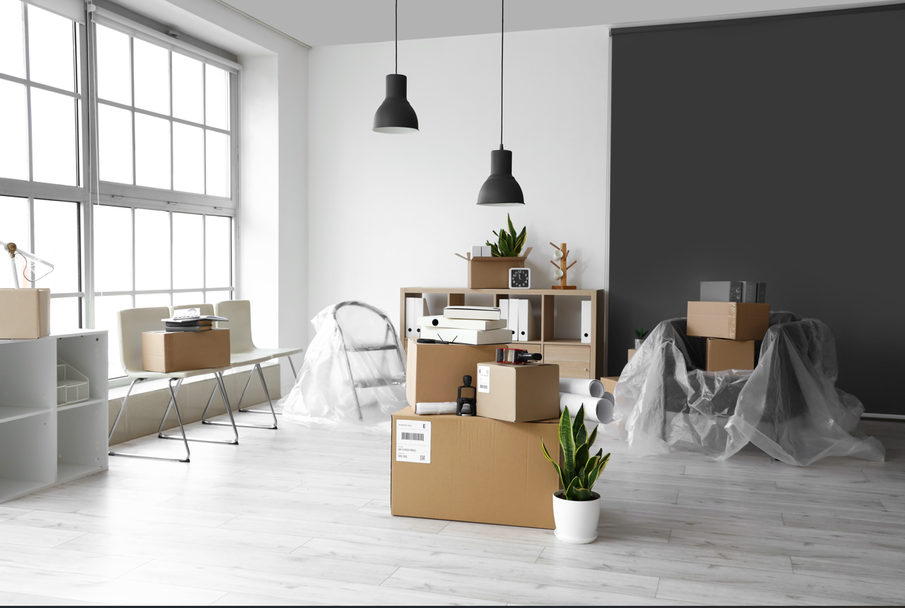 Empty office with moving boxes, white walls, and a large window.