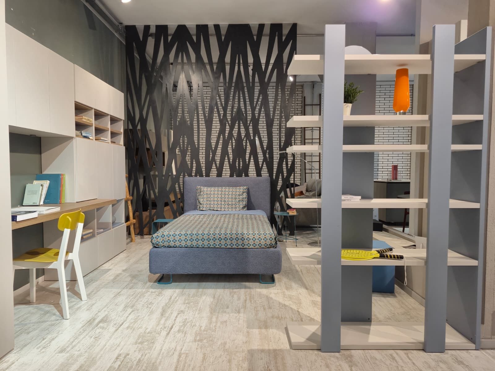 Una camera da letto moderna con letto, scaffali, scrivania e pannello decorativo a parete.