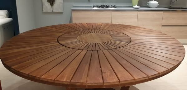 Grande tavolo rotondo in legno con superficie decorata. Mobili da cucina e decorazioni sullo sfondo.