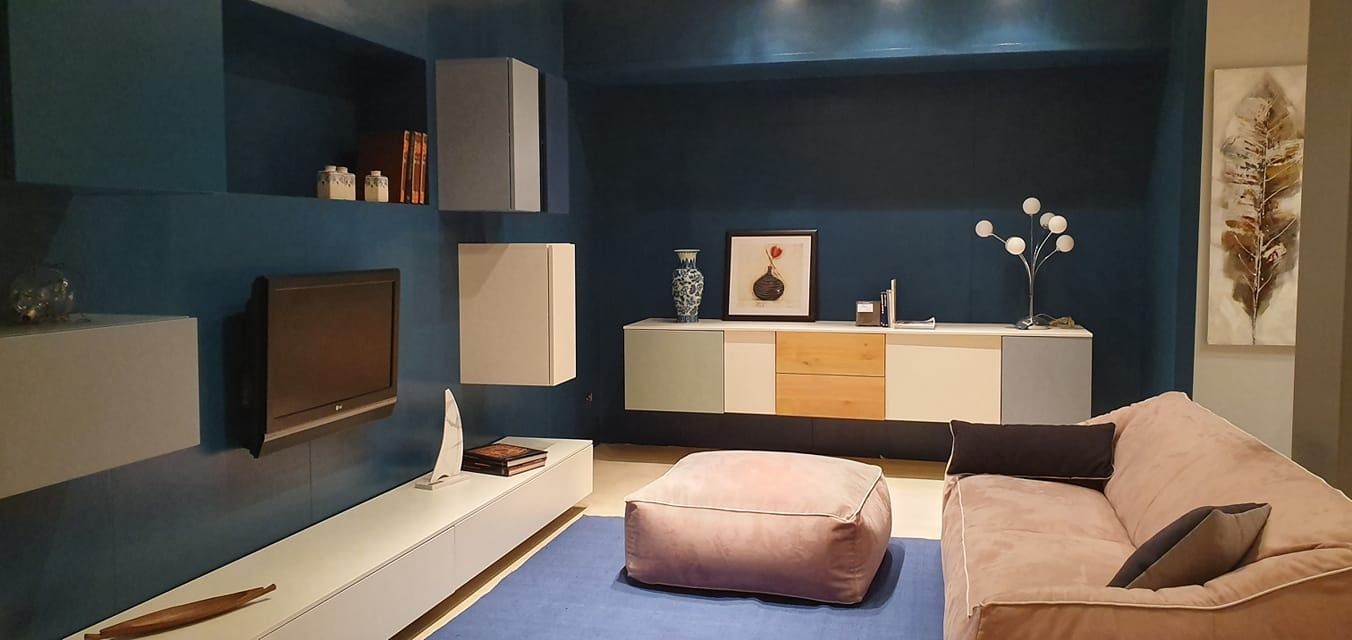 Soggiorno moderno con pareti blu, mobili grigio chiaro e in legno e un divano marrone.