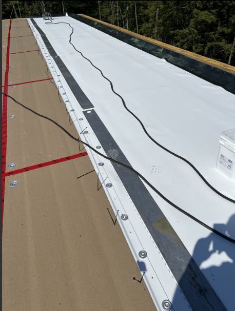 Un toit blanc est en train d'être installé sur un bâtiment