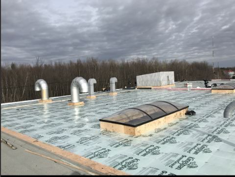 Un toit avec une lucarne et beaucoup de tuyaux dessus.