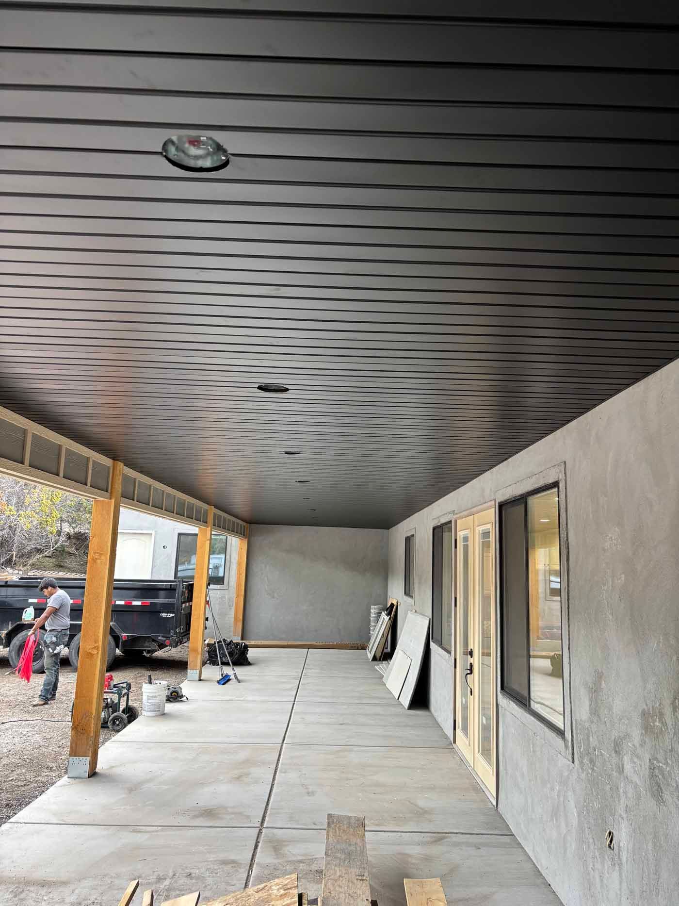 A porch with a black ceiling and a concrete floor.